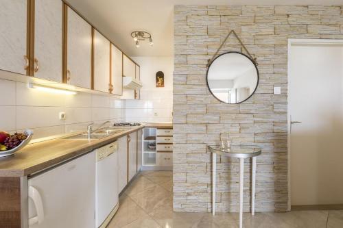 - une cuisine avec des placards blancs et un mur en pierre dans l'établissement Apartments Matea - 20m from sea, à Bol