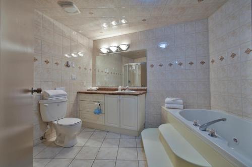 a bathroom with a tub and a toilet and a sink at King Hotel in Palmerston