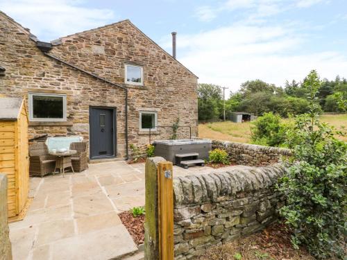 a stone cottage with a stone retaining wall and a patio at Overlea Cowshed in Highpeak Junction