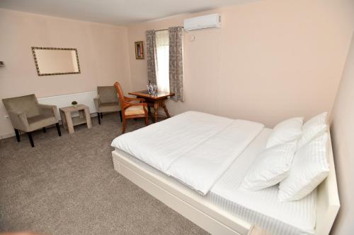 1 dormitorio con 1 cama blanca, mesa y sillas en Alijansa, en Čačak