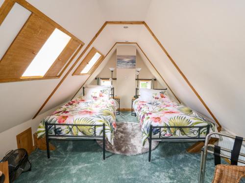 deux lits dans une chambre mansardée avec fenêtres dans l'établissement Lizzies Cottage, à Horncastle