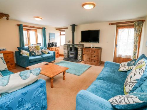 a living room with blue couches and a tv at The Shippon in Barnstaple