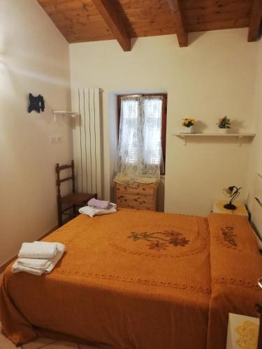 a bedroom with a large orange bed with a window at Agriturismo Ghirlanda Norma Rita in Carrodano Inferiore