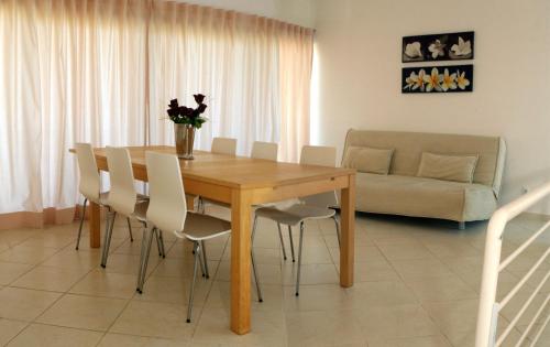 a dining room table with white chairs and a couch at Villas Oceano in Albufeira
