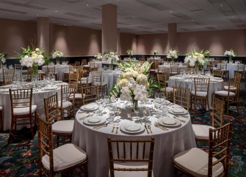 a ballroom with tables and chairs with white tablecloths at Graduate by Hilton Fayetteville, AR in Fayetteville