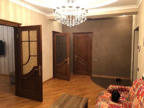 een woonkamer met 2 deuren en een kroonluchter bij For our friends Center 2 bedrooms in Baku