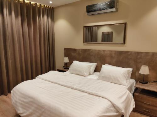 卡拉奇的住宿－Hamsun Shahrah-e-Faisal，卧室配有一张带白色床单和枕头的大床。