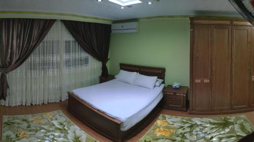 1 dormitorio con cama blanca y armario de madera en Maadi Apartment - 3 rooms ( Families Only ) en El Cairo