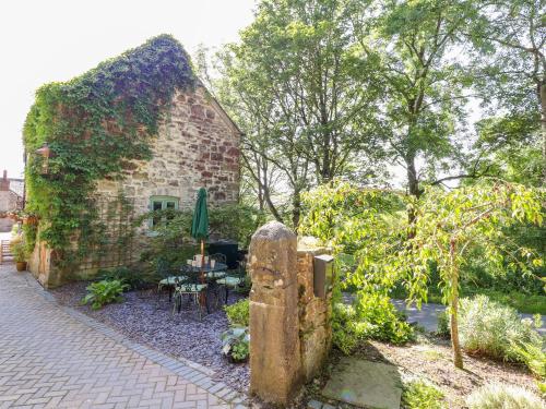 a brick building with a table and chairs in a garden at The Old Coach House in Mold