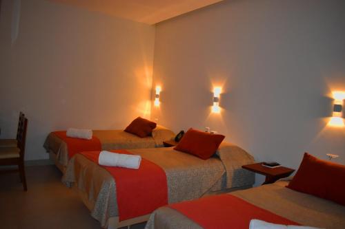 a hotel room with three beds and lights on the wall at Hotel Boutique Vendimia in Tarija