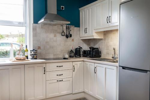 a kitchen with white cabinets and a refrigerator at Doorly Park in Sligo