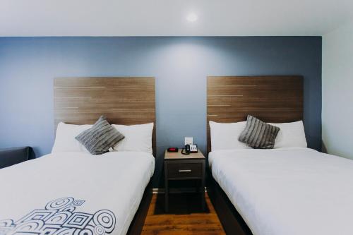 two beds sitting next to each other in a room at Scottish Inn & Suites - Kemah Boardwalk in Kemah