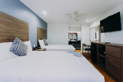 a hotel room with two beds and a flat screen tv at Scottish Inn & Suites - Kemah Boardwalk in Kemah