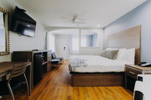 a hotel room with a bed and a desk and a kitchen at Scottish Inn & Suites - Kemah Boardwalk in Kemah