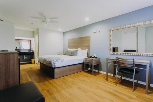 a bedroom with a bed and a desk and a mirror at Scottish Inn & Suites - Kemah Boardwalk in Kemah