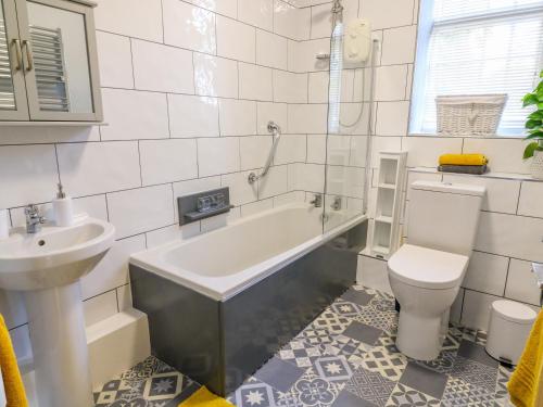 ein Badezimmer mit einer Badewanne, einem WC und einem Waschbecken in der Unterkunft Glebe Cottage in Skipton