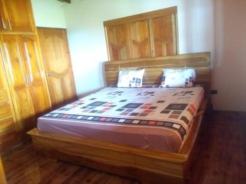 Bett mit einem Kopfteil aus Holz in einem Zimmer in der Unterkunft Finca campestre y recreativa los potrillos in Doradal