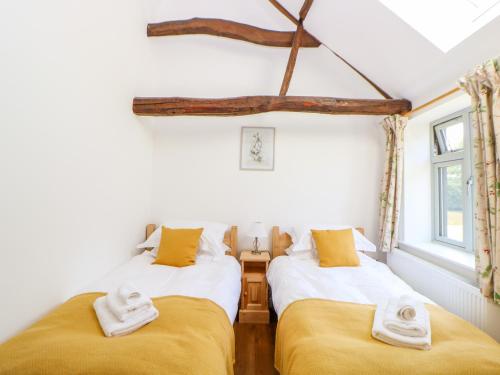 two beds in a room with yellow pillows at Sparrow Barn in Norwich
