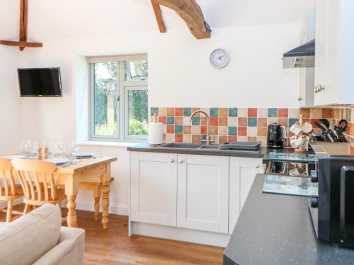 a kitchen with white cabinets and a table at Sparrow Barn in Norwich