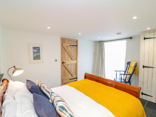 a bedroom with a bed with a yellow blanket at Manor House Barn in Camelford