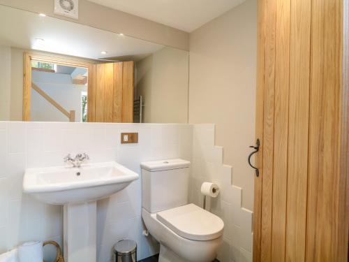 a bathroom with a white toilet and a sink at Manor House Barn in Camelford
