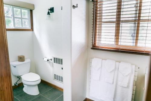 a bathroom with a toilet and a window and towels at Kilauea Lodge and Restaurant in Volcano