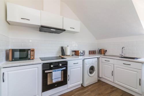 a kitchen with white cabinets and a washer and dryer at West Bridgford Classy 2bed Flat in Nottingham