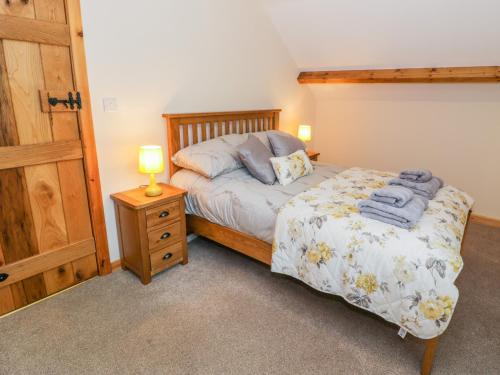a bedroom with a bed and a night stand with a lamp at Yr Hen Stabal in Blaenau-Ffestiniog