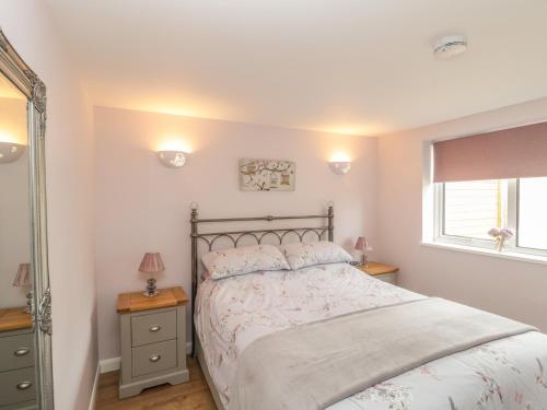 a bedroom with a bed and a window and a mirror at Cherry Tree Lodge in Axminster