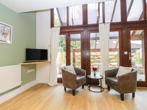a living room with two chairs and a television at The Forge in Winscombe