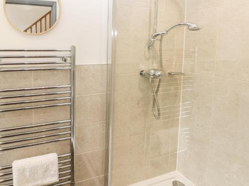 a shower with a glass door and a mirror at The Boathouse in Tenby