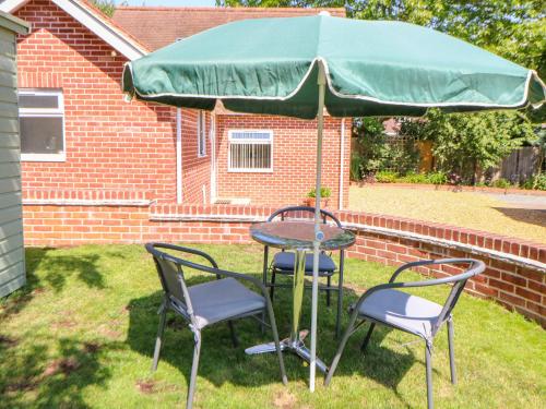 a table and two chairs under a green umbrella at The Lodge at Orchard House in Norwich