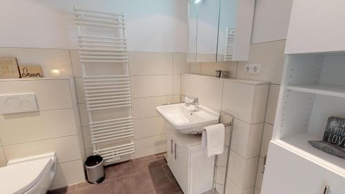 uma casa de banho branca com um lavatório e um WC em Villa Meeresrauschen Ostseetraum em Pelzerhaken
