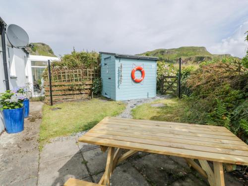 a blue shed with a red life preserver next to a wooden bench at Grebe Cottage in Oban