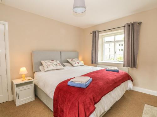a bedroom with a bed with a red blanket at Cutlers Cottage in Matlock