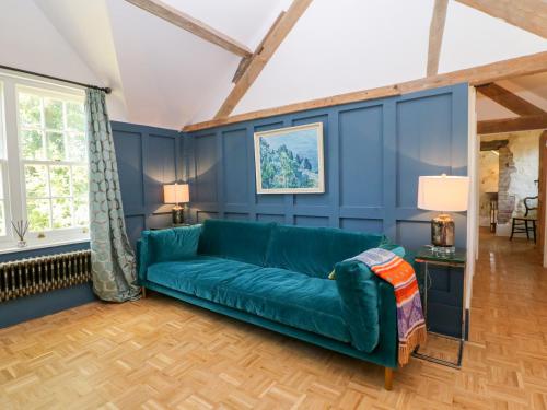 a green couch in a living room with blue walls at The Hemmel in Faringdon