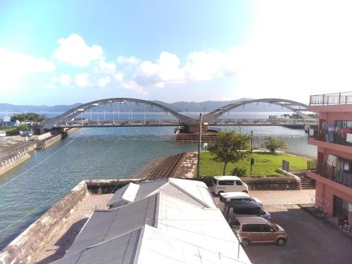 a bridge over a river with cars parked in front at Sakai Guest House AMAMI（堺ゲストハウス奄美） in Setouchi