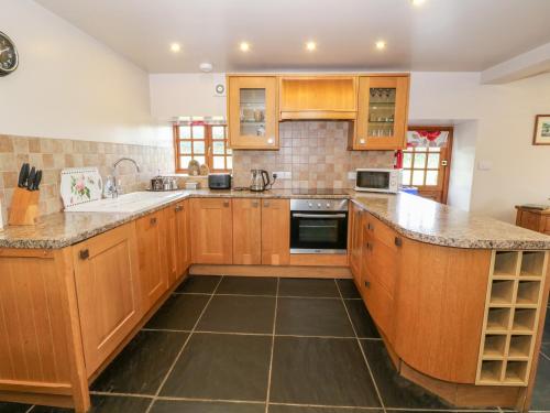 a kitchen with wooden cabinets and granite counter tops at Dysynni in Tywyn