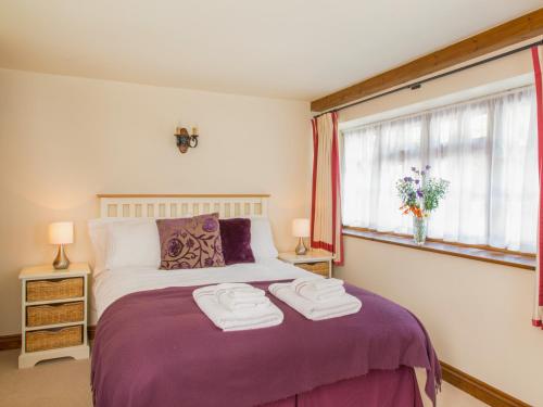Un dormitorio con una cama morada con toallas encima. en The Coach House, en Kingsbridge