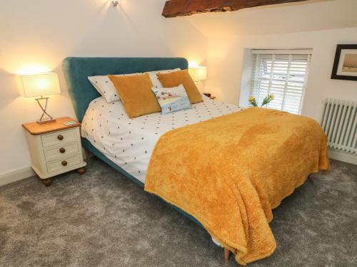 a bedroom with a bed with a yellow blanket and a night stand at Cockle Bay Cottage in Morecambe