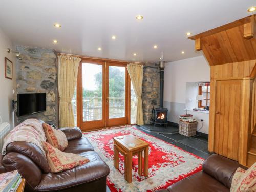 a living room with a leather couch and a fireplace at Dysynni in Tywyn
