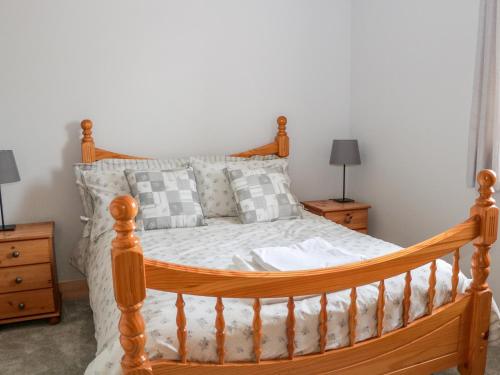 a bedroom with a wooden bed and two night stands at Teal Cottage in Melton Mowbray