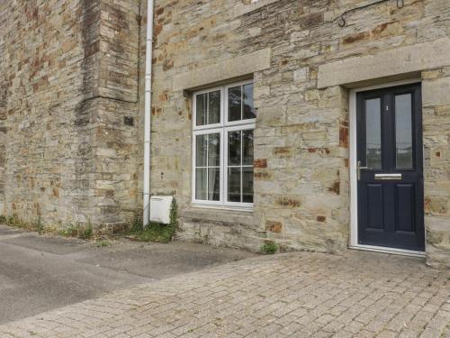 a brick building with a blue door and a window at Cherrywood Manor in Bodmin