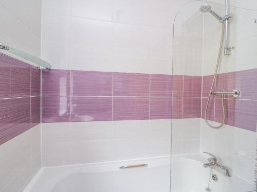 a bathroom with a tub and a shower with purple stripes at Hen Brynbedw in Llanybydder
