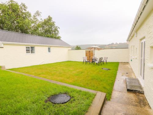 a backyard with a table and chairs and an umbrella at Hen Brynbedw in Llanybydder