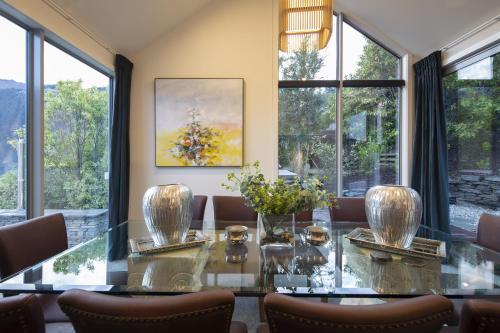 a dining room with a glass table and windows at Lago Infinito by Sotheby's Luxury Rental Homes in Queenstown