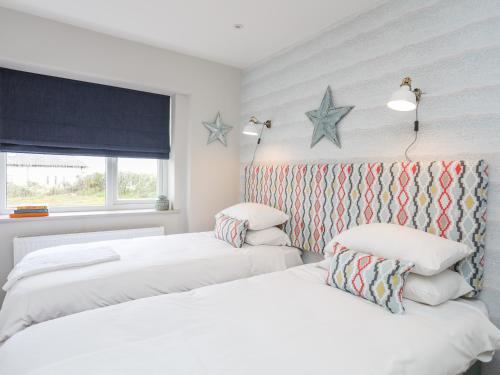 - 2 lits dans une chambre avec des étoiles sur le mur dans l'établissement Braid Apartment, à Trearddur