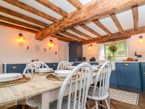 a kitchen with blue cabinets and a table with white chairs at Easter Cottage in Burford