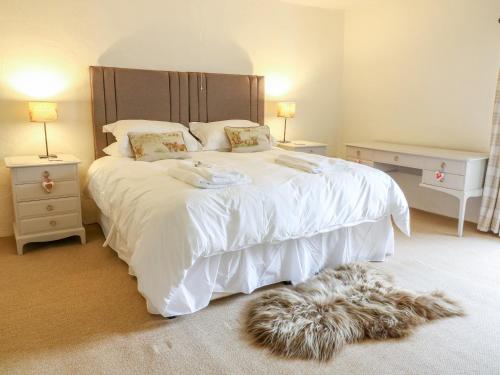 a bedroom with a large bed with white sheets and a rug at Church Farm Cottage in Skipton