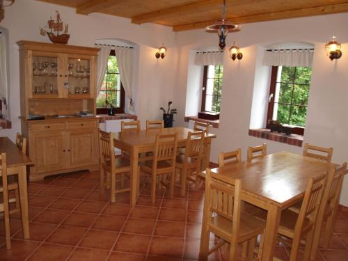 una cocina con mesas y sillas de madera y ventanas en Penzion Vital en Liberec